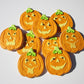 Pumpkin shaped cookies iced and stenciled with Jack-O-Lantern Halloween Faces Round Cookie Stencil Set by Designer Stencils