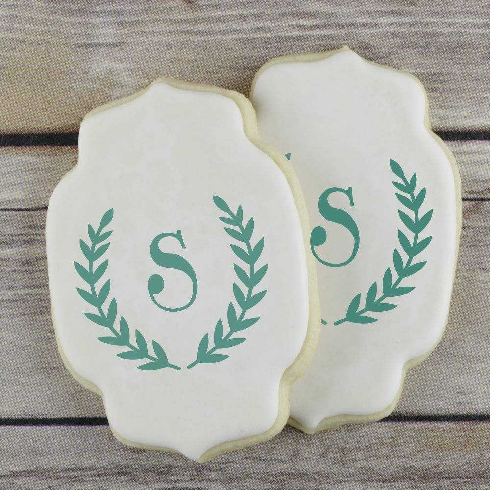 Decorated iced cookies with a monogram and laurel wreath embellishments